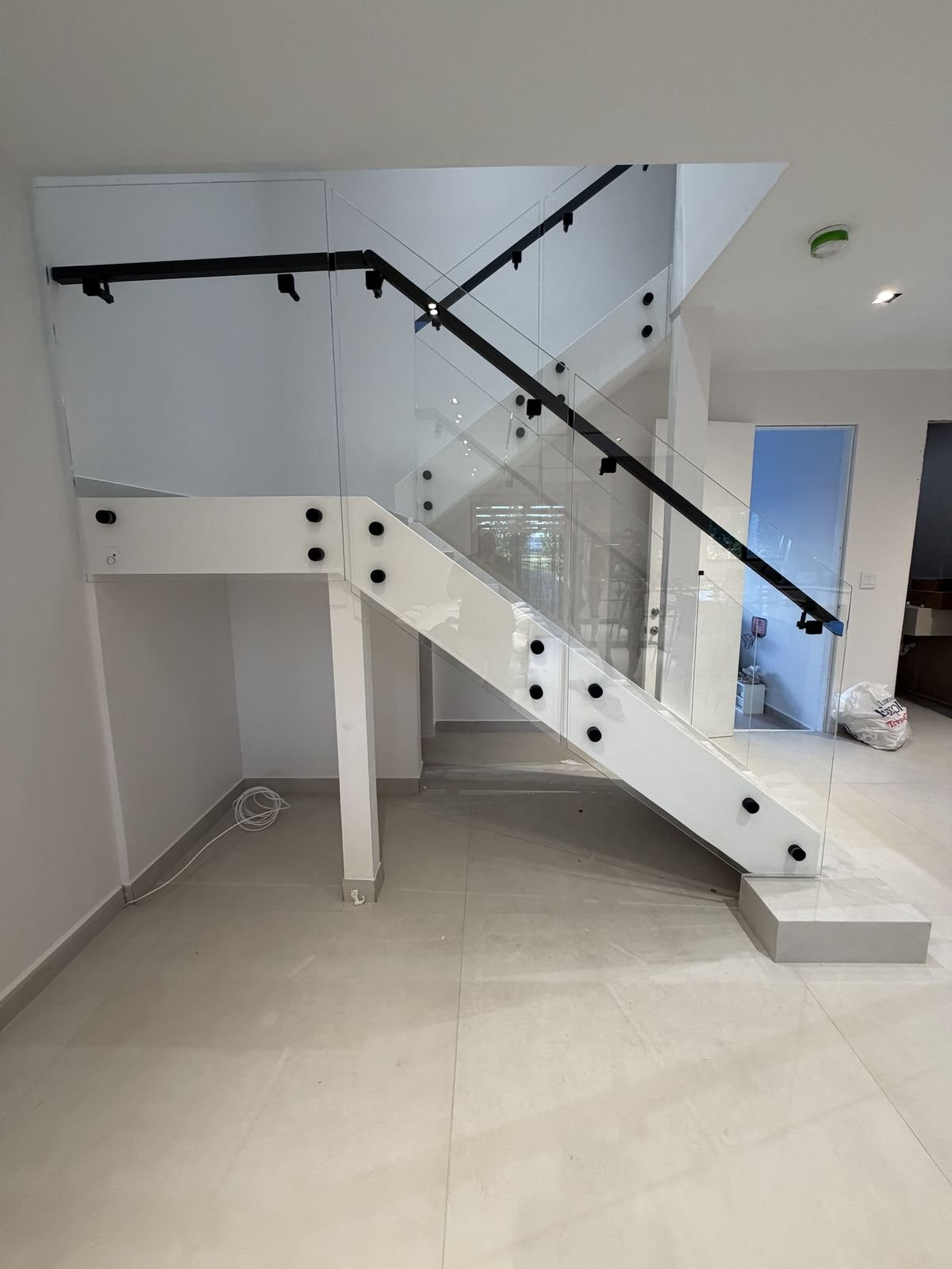 Glass stair railing with black standoffs and handrail