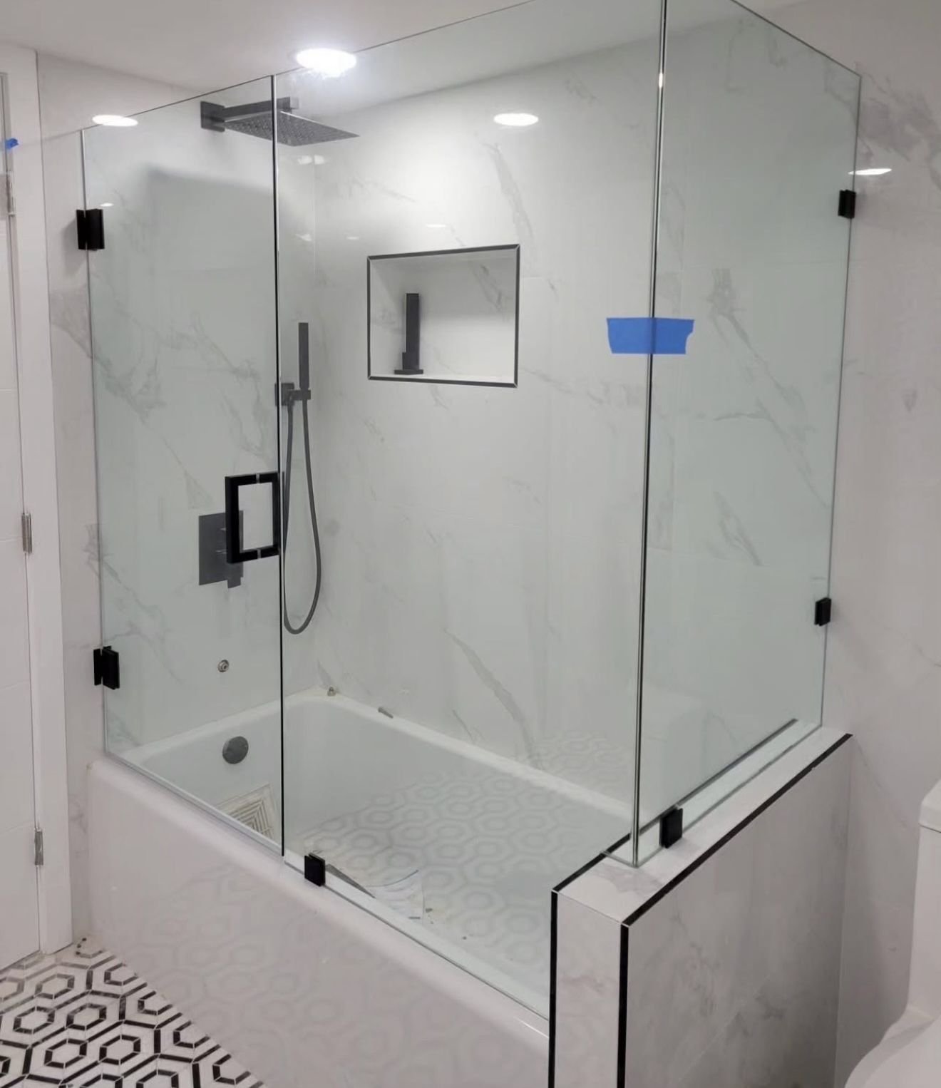 Glass tub enclosure with black clamps